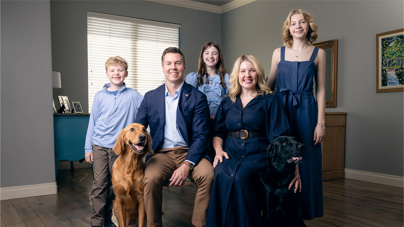 Adam Pugh, his wife, their three children, and their dogs posing at home