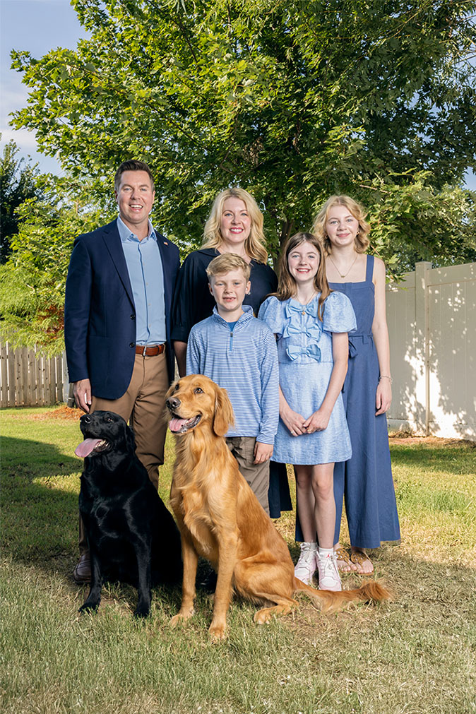 Adam Pugh, his wife, their three children, and their dogs standing outside